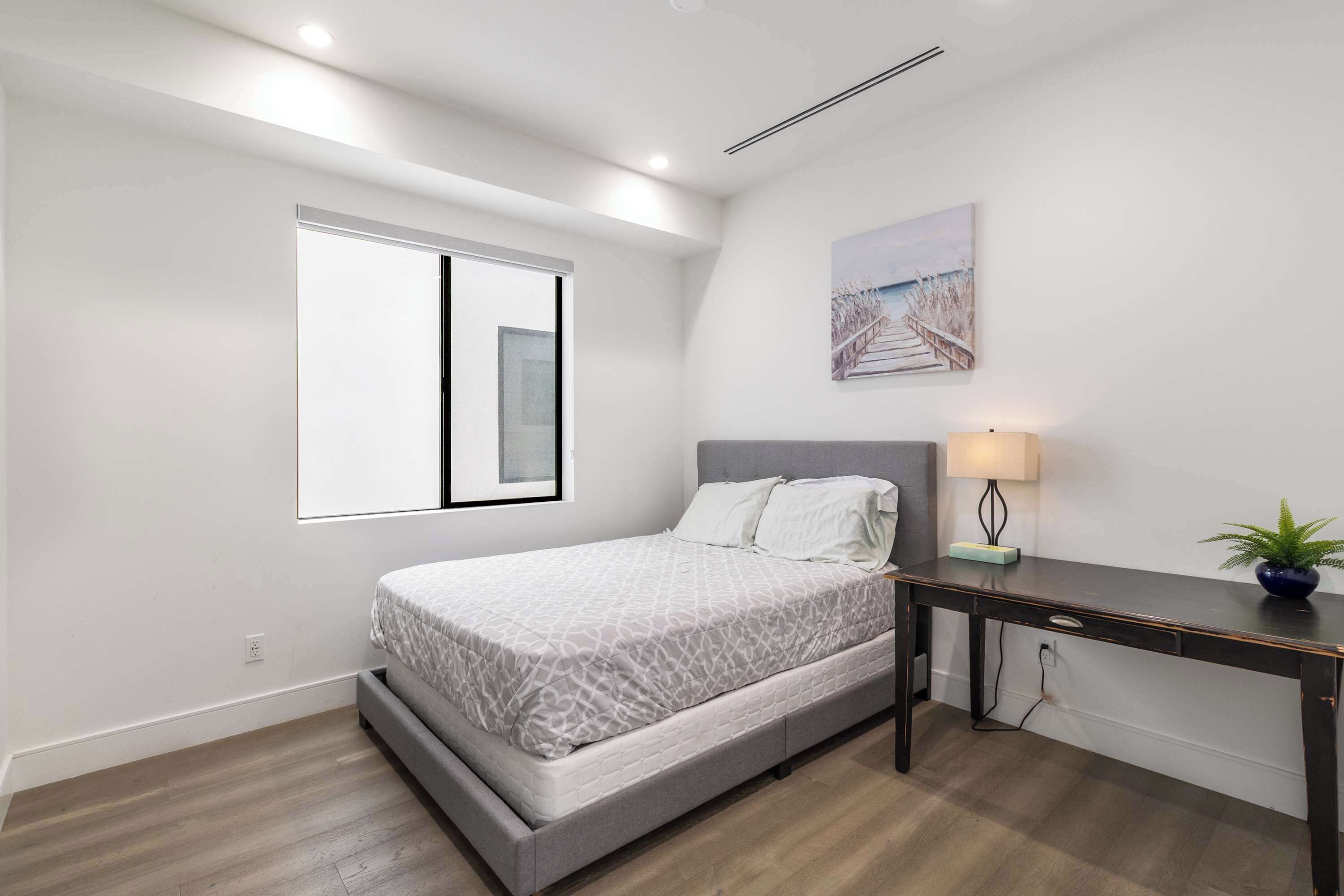 Une chambre à coucher avec un lit, un bureau, une lampe et une fenêtre.