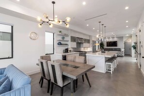A modern kitchen with a dining area, a large island, and a TV mounted on the wall.