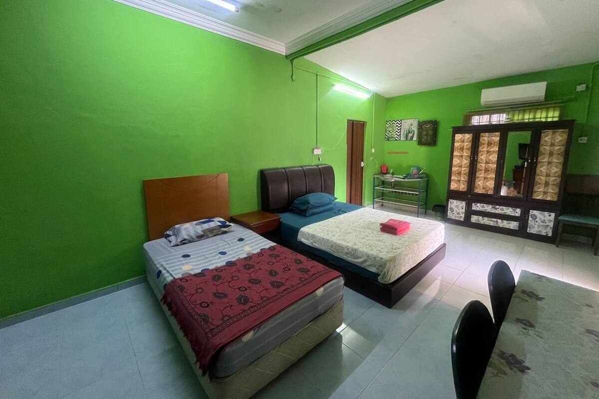 A room with two beds, a small table, a cabinet, and a mirror.