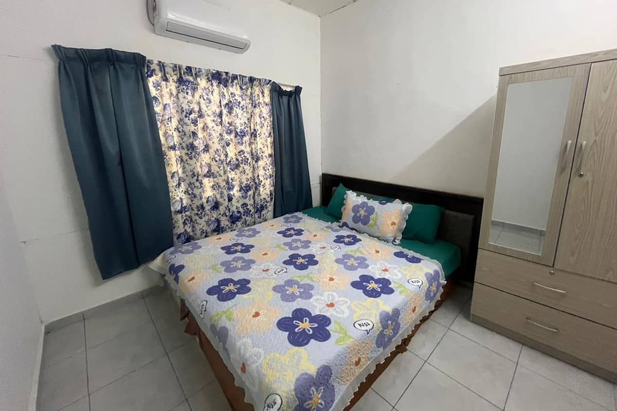 A bedroom with a bed, a wardrobe, a window with curtains, and an air conditioning unit.