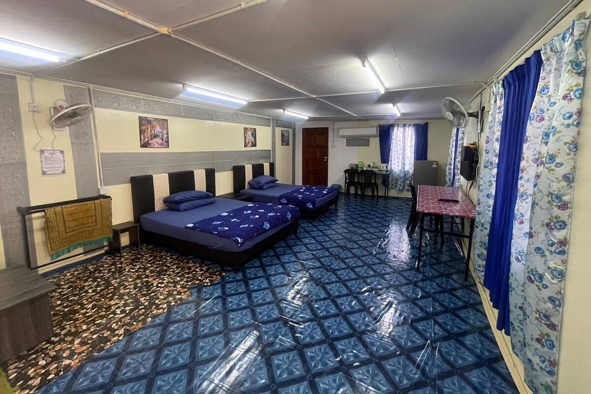 A room with two beds, a desk, a chair, and a small table.