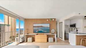 Ein modernes Apartment mit Balkon, einer Küche und einem großen Fernsehbildschirm, das eine schöne Aussicht zeigt.