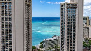 Ein Hochhaus-Hotel mit mehreren Etagen mit Blick auf einen Strand und klares, blaues Wasser sowie Boote.