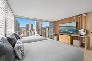 A modern bedroom with two beds, a large TV, and a view of the cityscape.