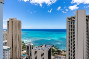 A high-rise hotel overlooking a beach with clear blue waters and a view of the ocean.