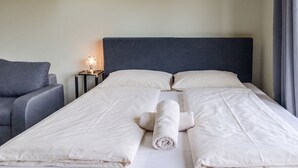 A hotel room with a bed, a nightstand, a lamp, a chair, and a skylight. - Comfy Room in Shared Villa w/ Free Parking (Wien)