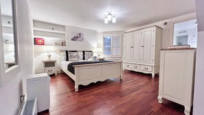 A bedroom with a bed, bedside tables, a radiator, and a wardrobe.