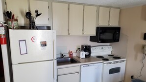 A compact kitchen with a refrigerator, microwave, stove, and sink.