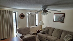 A living room with a ceiling fan, two sofas, a coffee table, and a lamp.