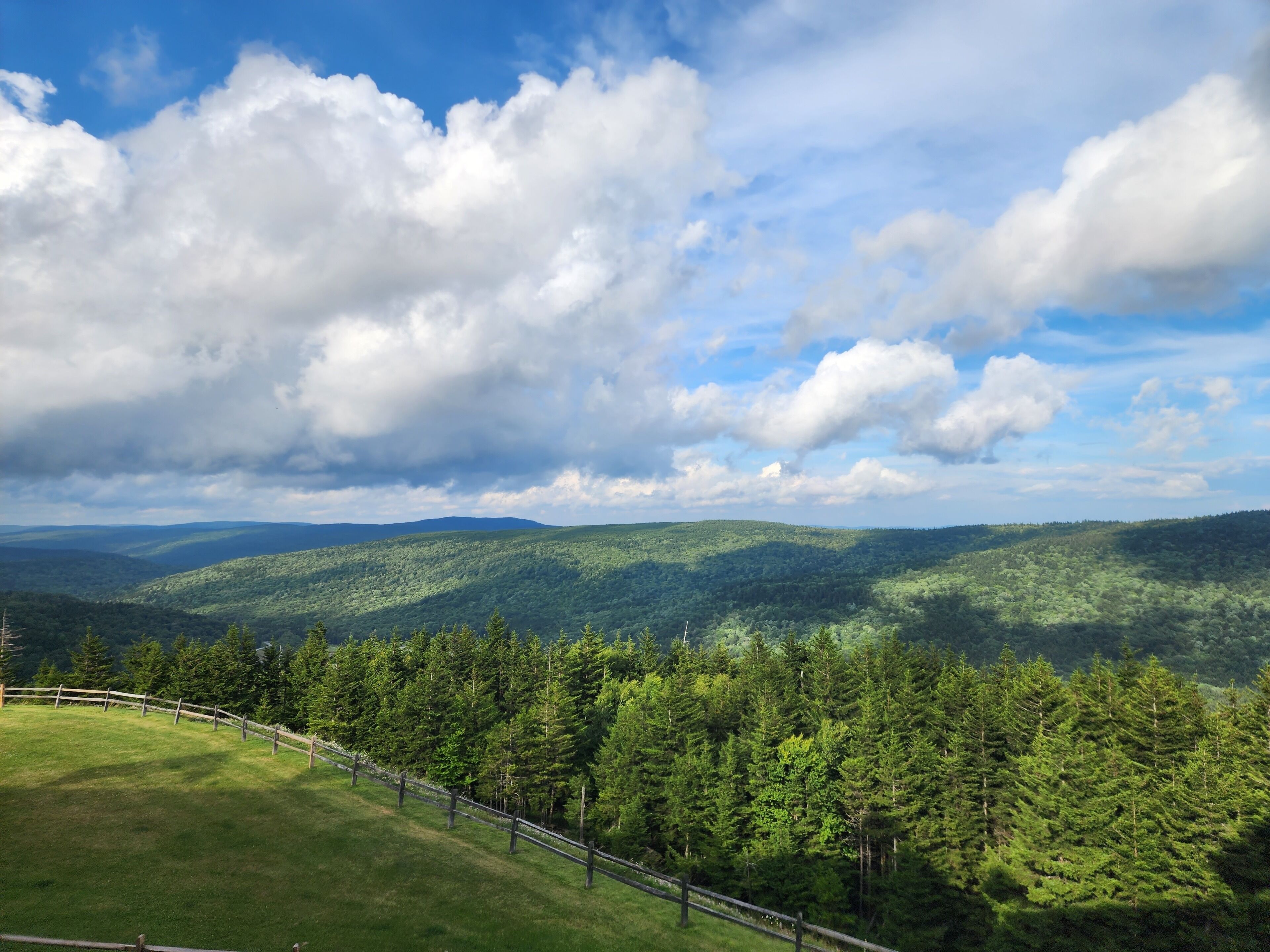 A panoramic view of a mountainous landscape with dense forests and a clear sky.