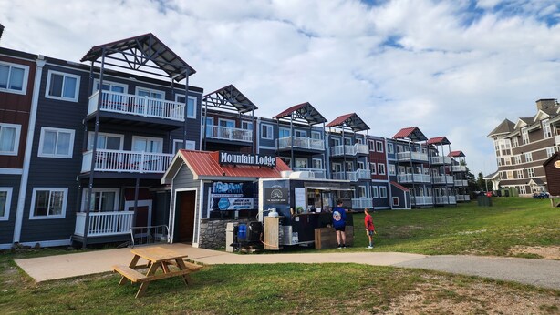 A multi-story residential building with balconies, a coffee shop, and a picnic table.
