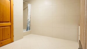 A bathroom with a wooden door, tiled walls, and a shower area.