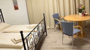 A hotel room with a bed, a round table with chairs, a ceiling light, and curtains.