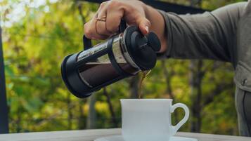 Eine Hand gießt Kaffee in eine weiße Tasse auf einem Untertasse.