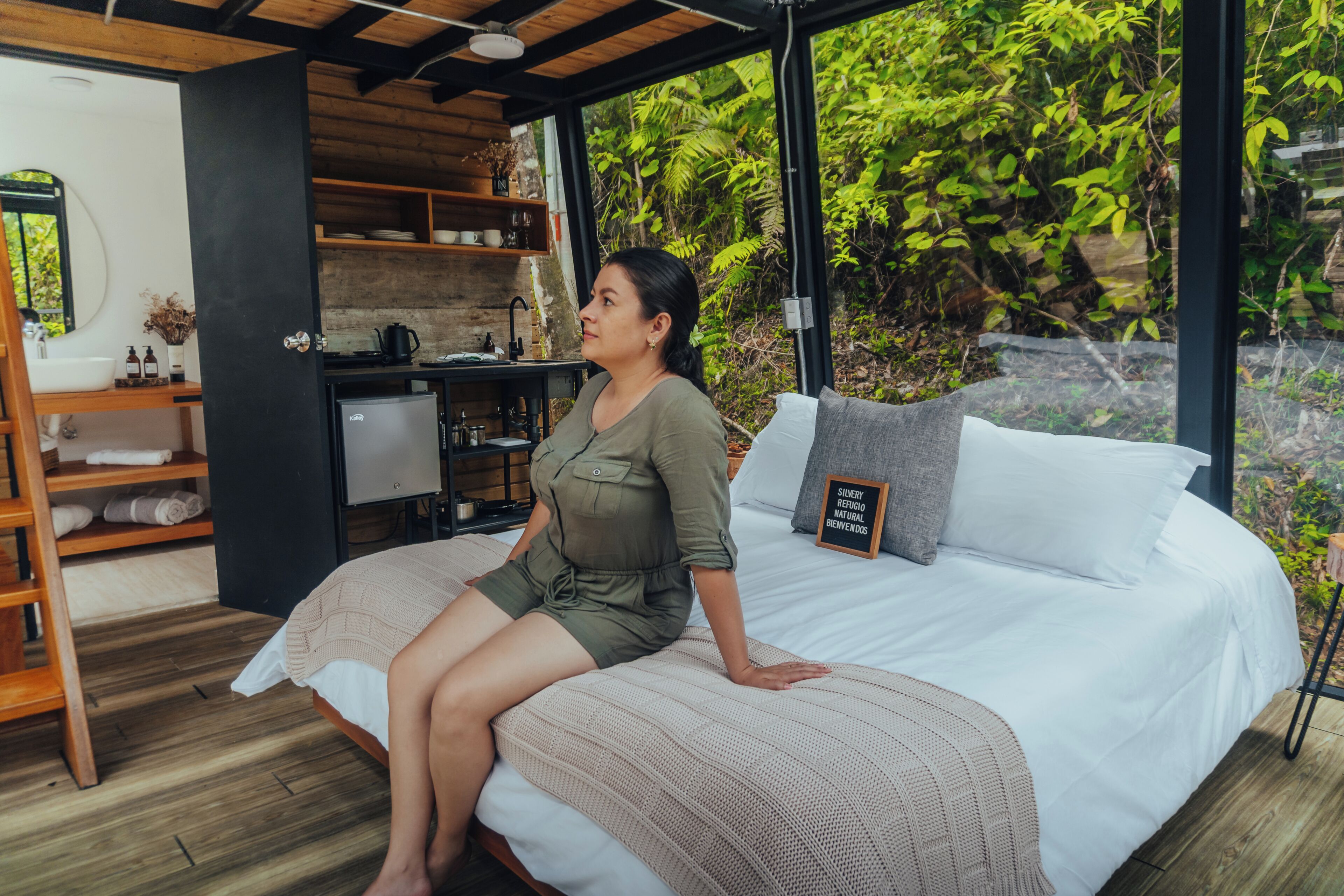 A room with a bed, a desk, and a view of greenery.