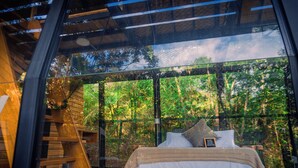 Quarto com uma janela grande, uma cama de madeira e uma escada.