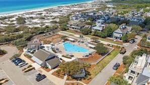 Vista aérea de una zona residencial costera con casas, piscina y playa.