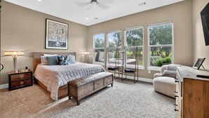 A bedroom with a bed, bedside tables, a bench, a desk, and large windows. - Hill Country Retreat & Casita (Horseshoe Bay)
