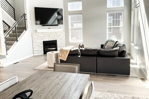 A modern living room with a fireplace, a sofa, a TV, and a dining area. - Modern Mountain Retreat Sleeps 10 Park City (Daniel)