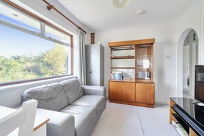 Un salon moderne avec un canapé, une bibliothèque en bois et un téléviseur.