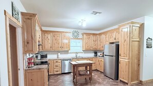 A kitchen with wooden cabinets, stainless steel appliances, and a tiled floor.