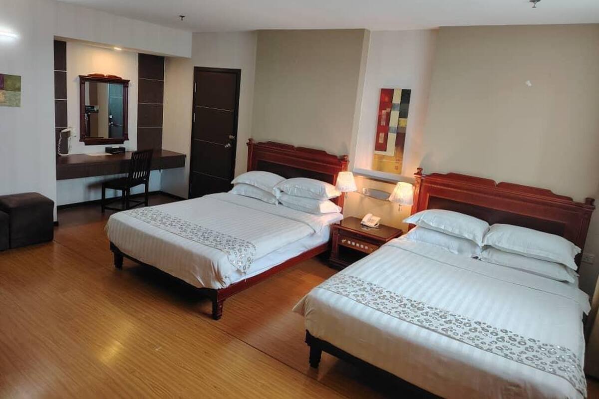 Una habitación de hotel con dos camas, un escritorio con silla, un espejo y un armario.