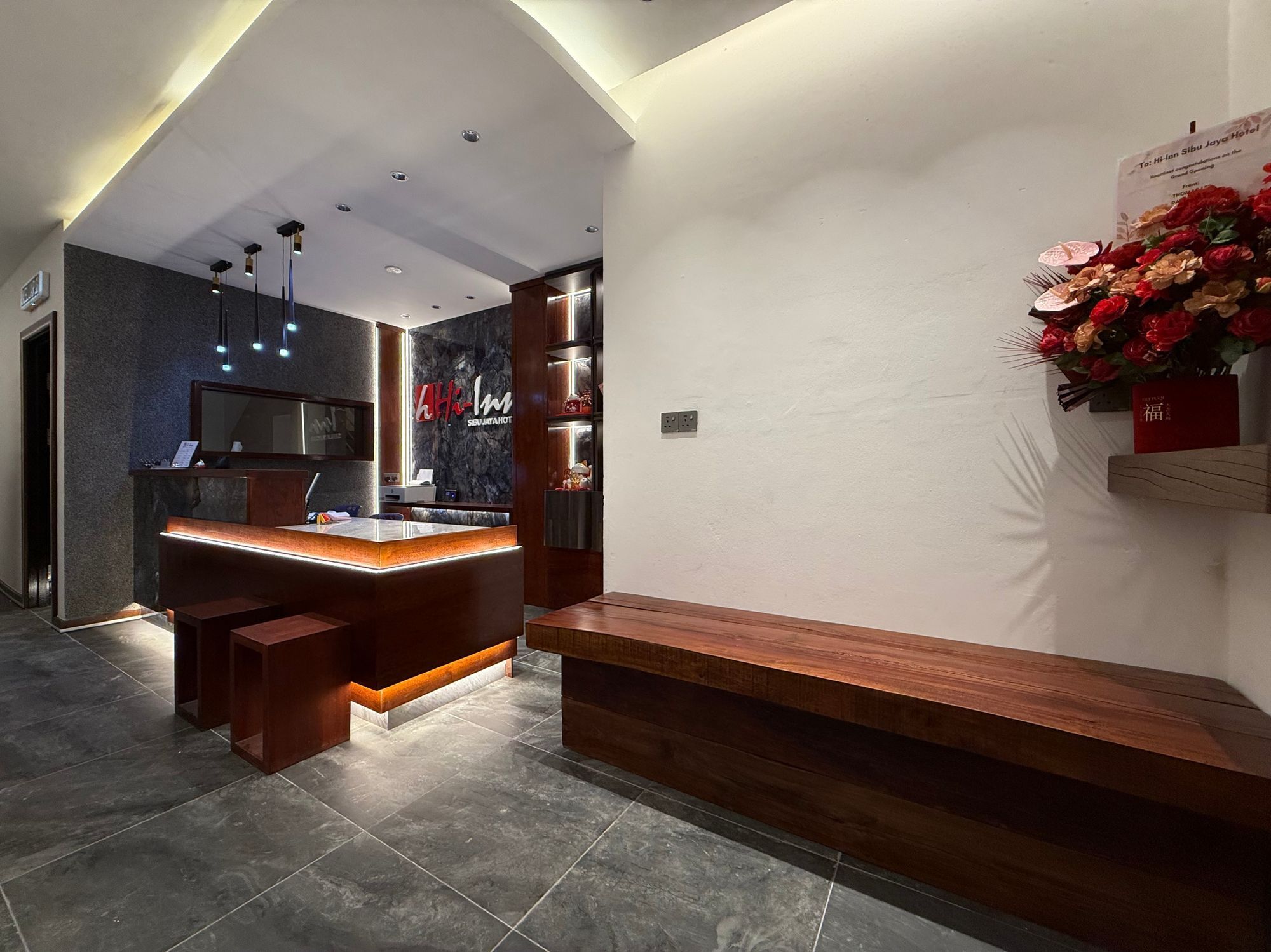 Eine moderne Hotellobby mit einer Rezeption, einer Sitzecke und einer Wanddekoration aus Blumen.