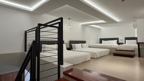 A modern bedroom with a loft-style design, featuring a staircase, multiple beds, and recessed lighting. - OYO 91193 Hi Inn Sibu Jaya (Sibu)