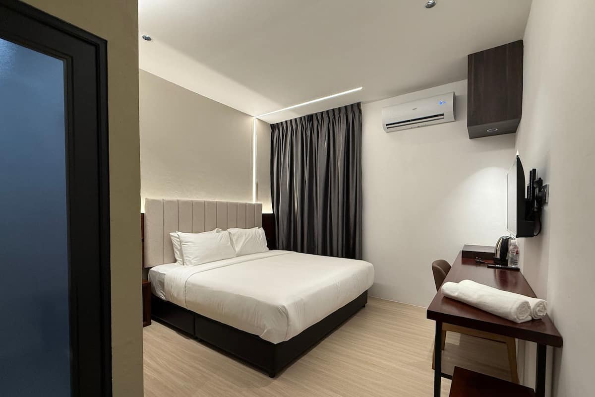 Una habitación de hotel moderna con una cama, un escritorio, una silla, un televisor y un equipo de aire acondicionado.