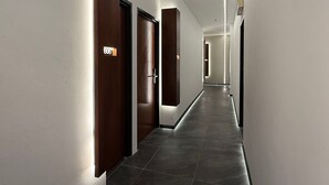 A modern hotel hallway with dark wooden doors, a clean white wall, and a tiled floor. - OYO 91193 Hi Inn Sibu Jaya (Sibu)