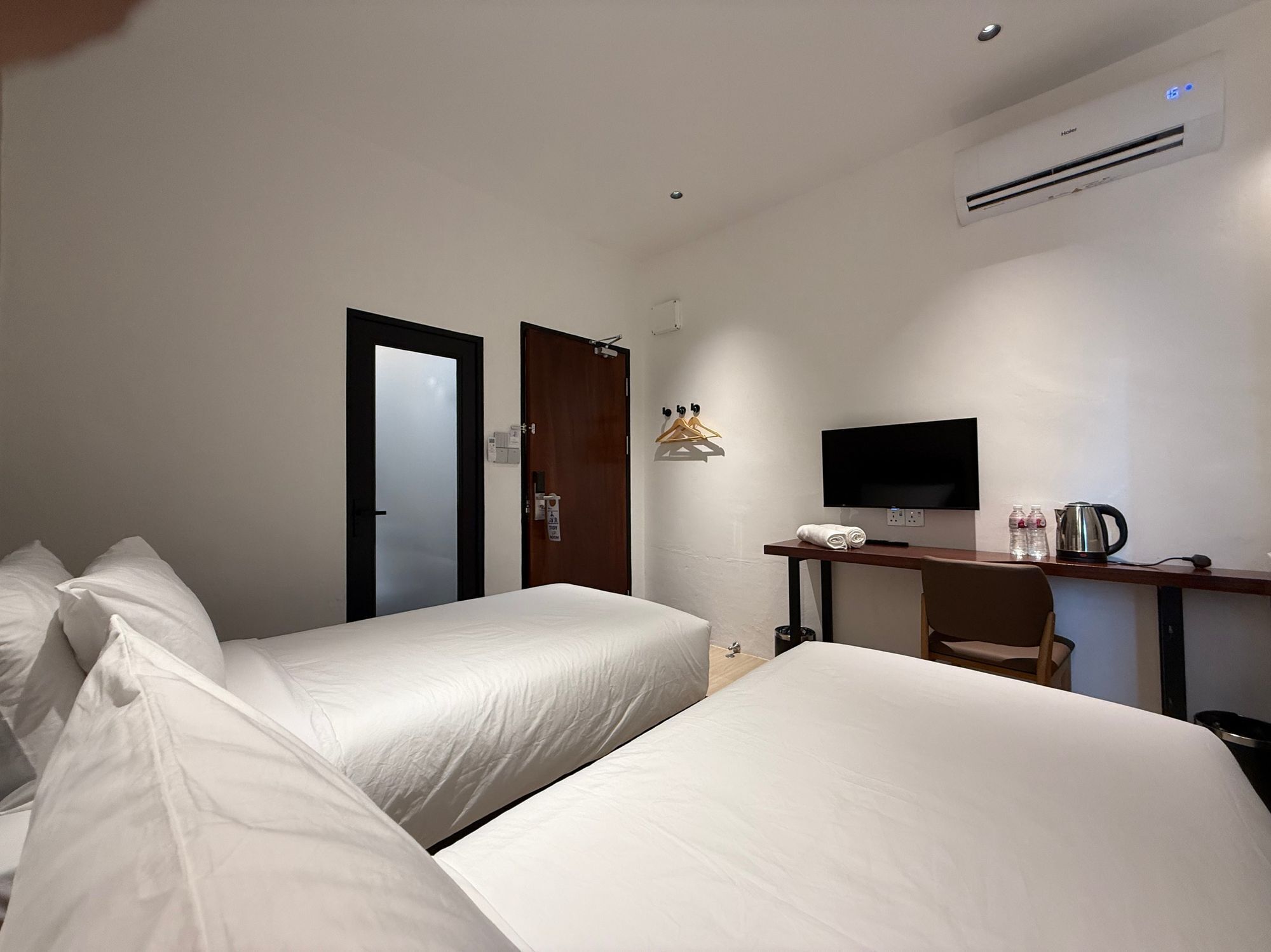 Een hotelkamer met twee bedden, een bureau, een flatscreen televisie, een waterkoker en een koffiezetapparaat.