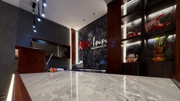 A modern hotel lobby with a marble reception desk, a large wall-mounted sign for 'Sibu Jaya Hotel', and a display of red flowers and traditional decorations. - OYO 91193 Hi Inn Sibu Jaya (Sibu)
