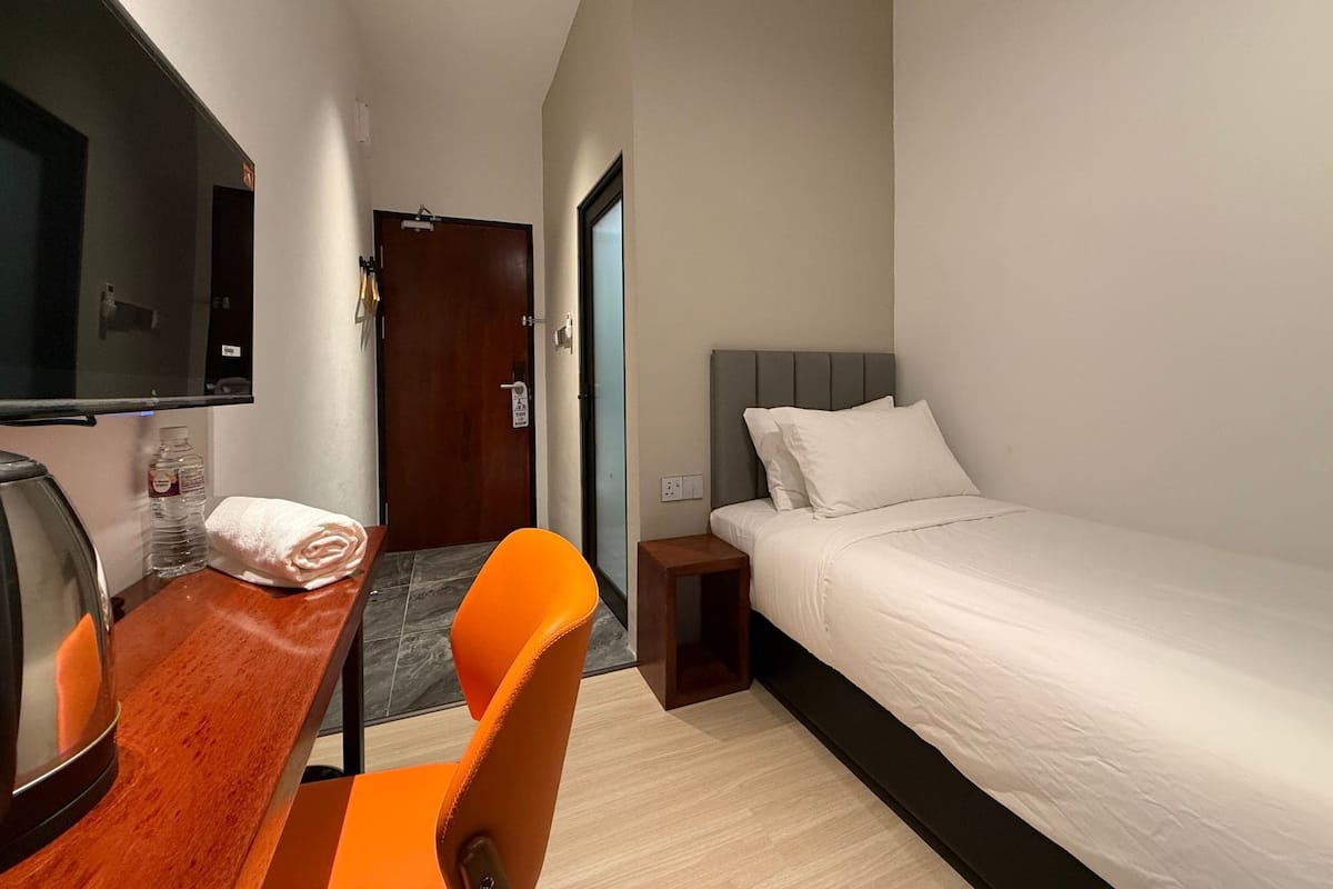Una habitación de hotel con cama, escritorio, silla, televisor y puerta.