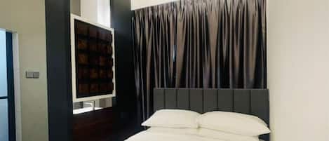 Un dormitorio moderno con una cama grande, un armario empotrado y una pequeña zona de estar.