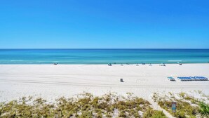 A wide sandy beach with a clear blue sky and calm sea.