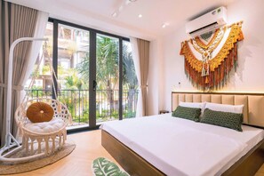 A hotel room with a bed, a hanging chair, and a view of the outdoors. - FLAMINGO HAI TIEN-SEA VIEW (Hoang Tien)