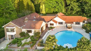 A residential property with a swimming pool, multiple houses, and a well-maintained garden.