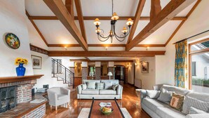 A spacious living room with a fireplace, a sofa set, a coffee table, and a chandelier.