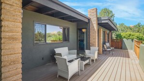 Un patio cubierto al aire libre con muebles de mimbre y una terraza de madera.