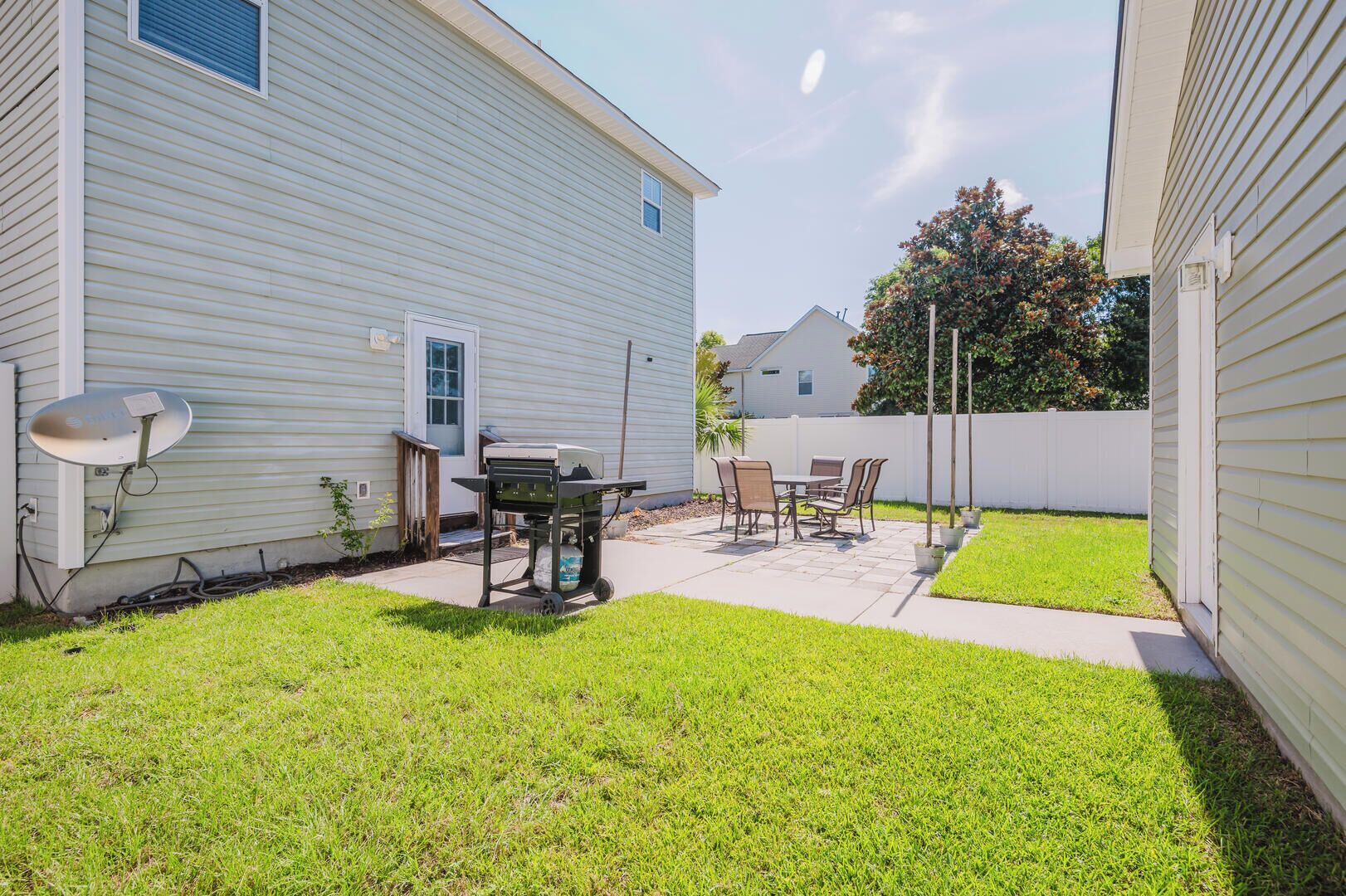 A backyard with a patio, a grill, and a satellite dish.