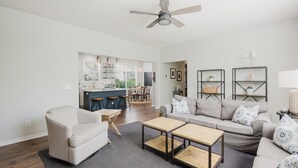 A spacious living room with a sofa, coffee table, and a dining area in the background. - Bluffton Magnolia House (Bluffton)