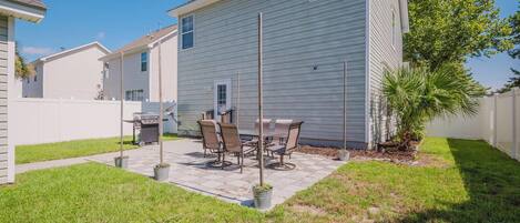 A residential backyard with a patio, outdoor furniture, and a grill.