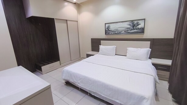 Una habitación de hotel moderna con una cama grande, un armario, una mesita de noche y un cuadro en la pared.