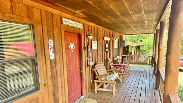 Una cabaña de madera con una puerta roja marcada '46', un porche con sillas de madera y un cartel que dice 'Lonesome Dove Texas Pop. 191'.