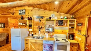 Una cocina rústica con armarios de madera, un refrigerador, un microondas y una estufa.