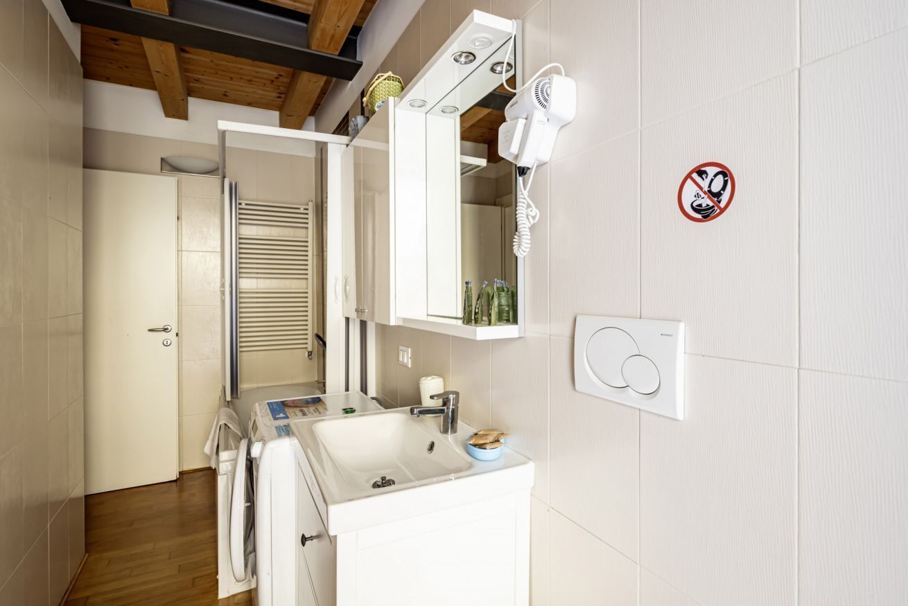 Une salle de bain moderne équipée d’un lavabo, d’un miroir, d’un sèche-cheveux et d’un panneau indiquant qu’il est interdit de fumer.