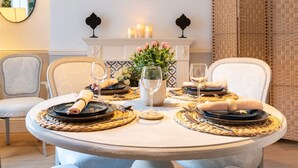 A round dining table set for four with woven placemats, black plates, and white napkins. A vase with pink flowers is centered on the table. - Beautiful Townhouse Harrogate, 3 bedroom (Harrogate)