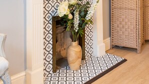 A room with a white fireplace, a large wall clock, and a woven basket. - Beautiful Townhouse Harrogate, 3 bedroom (Harrogate)