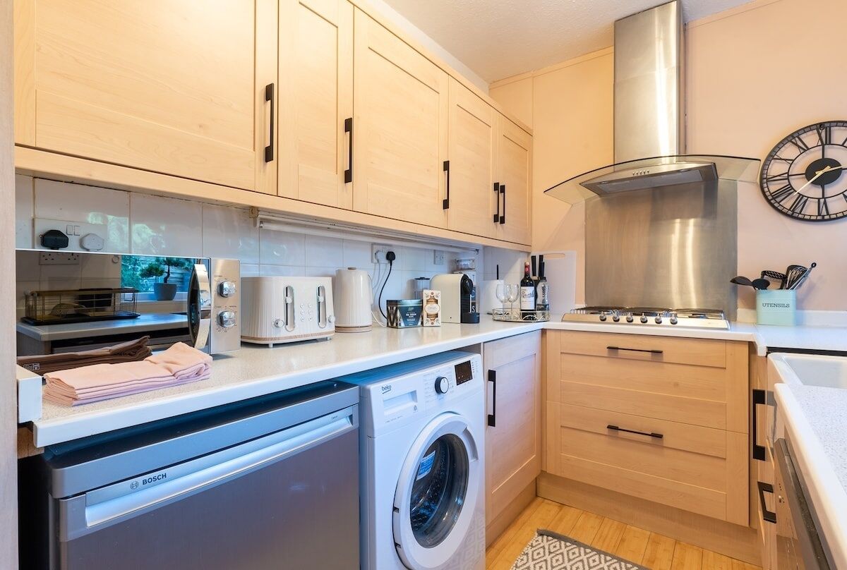 A modern kitchen with a Bosch washing machine, a microwave, a toaster, and a stove.