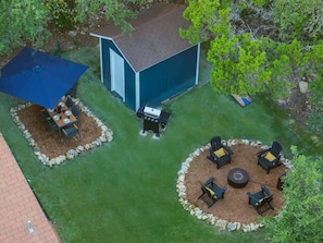 A backyard with a barbecue area, a shed, and a circular seating arrangement with chairs and a fire pit. - Stagecoach Breeze | Lake View•Firepit•Pet Friendly (Canyon Lake)